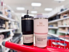 2 stanley quencher tumblers sitting on top a target cart