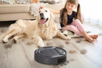 A large dog and a little girl sit on a floor that is being cleaned by the Lefant M210 robotic vacuum cleaner.
