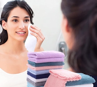 A woman washing her face with a makeup towel.