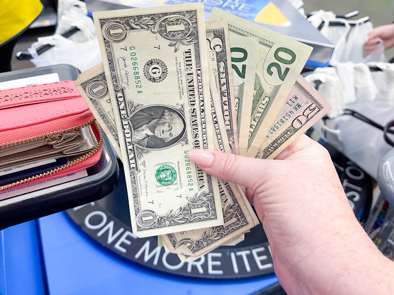 a person holding cash to pay for groceries