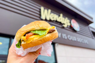 cheeseburger being held up in front of wendys