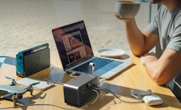 a person on a laptop with a power station at a table at a beach