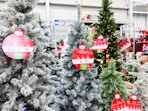In-store photo taken of Walmart's Christmas tree area featuring the Holiday Time flocked 6-ft tree