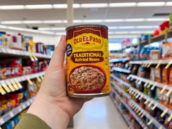 hand holding a can of old el paso refried beans in store aisle