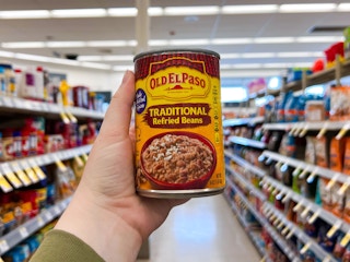 hand holding a can of old el paso refried beans in store aisle