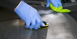 person scrubbing a car seat with a brush