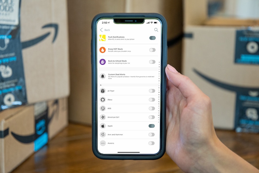 a person's hand holding up a phone showing how to set up amazon deal alerts with the krazy coupon lady app