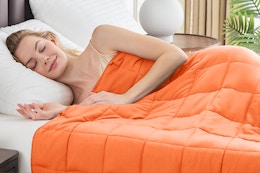 Woman sleeping with an orange weighted blanket.