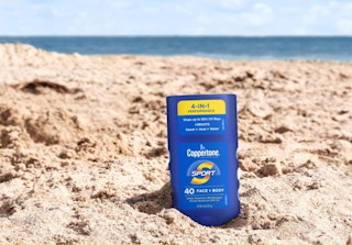 a blue sunscreen stick in sand