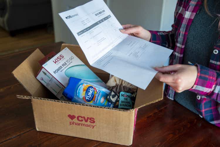 A person holding a cvs online order receipt over an open CVS box with products inside