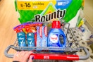 person pushing a cart with bounty paper towels, persil detergent, colgate toothpaste, degree deodorant, and reese's candy in it