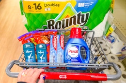 person pushing a cart with bounty paper towels, persil detergent, colgate toothpaste, degree deodorant, and reese's candy in it