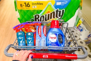 person pushing a cart with bounty paper towels, persil detergent, colgate toothpaste, degree deodorant, and reese's candy in it