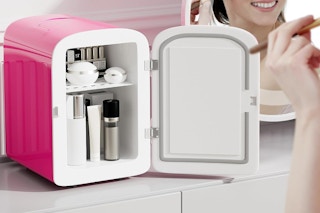 a pink mini fridge filled with products on a counter 