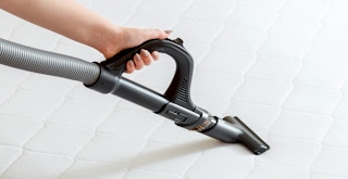 person using vacuum extension to clean mattress