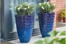 Lifestyle image of two colbalt blue textured planters outdoors 