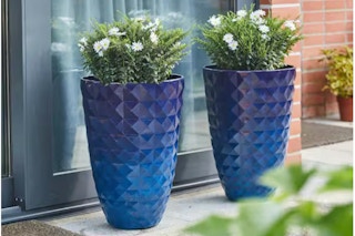 Lifestyle image of two colbalt blue textured planters outdoors