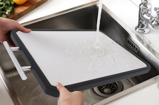 Person washing the New England Stories Titanium Cutting Board in the sink.