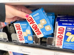 hand grabbing a pack of band-aid bandages off a target shelf