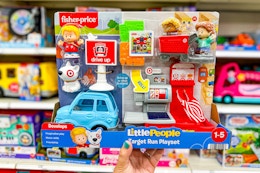 hand holding a little people target run playset in front of shelves