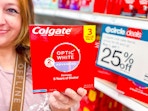 hand holding a colgate optic white 3-pack in front of target signage