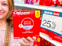 hand holding a colgate optic white 3-pack in front of target signage