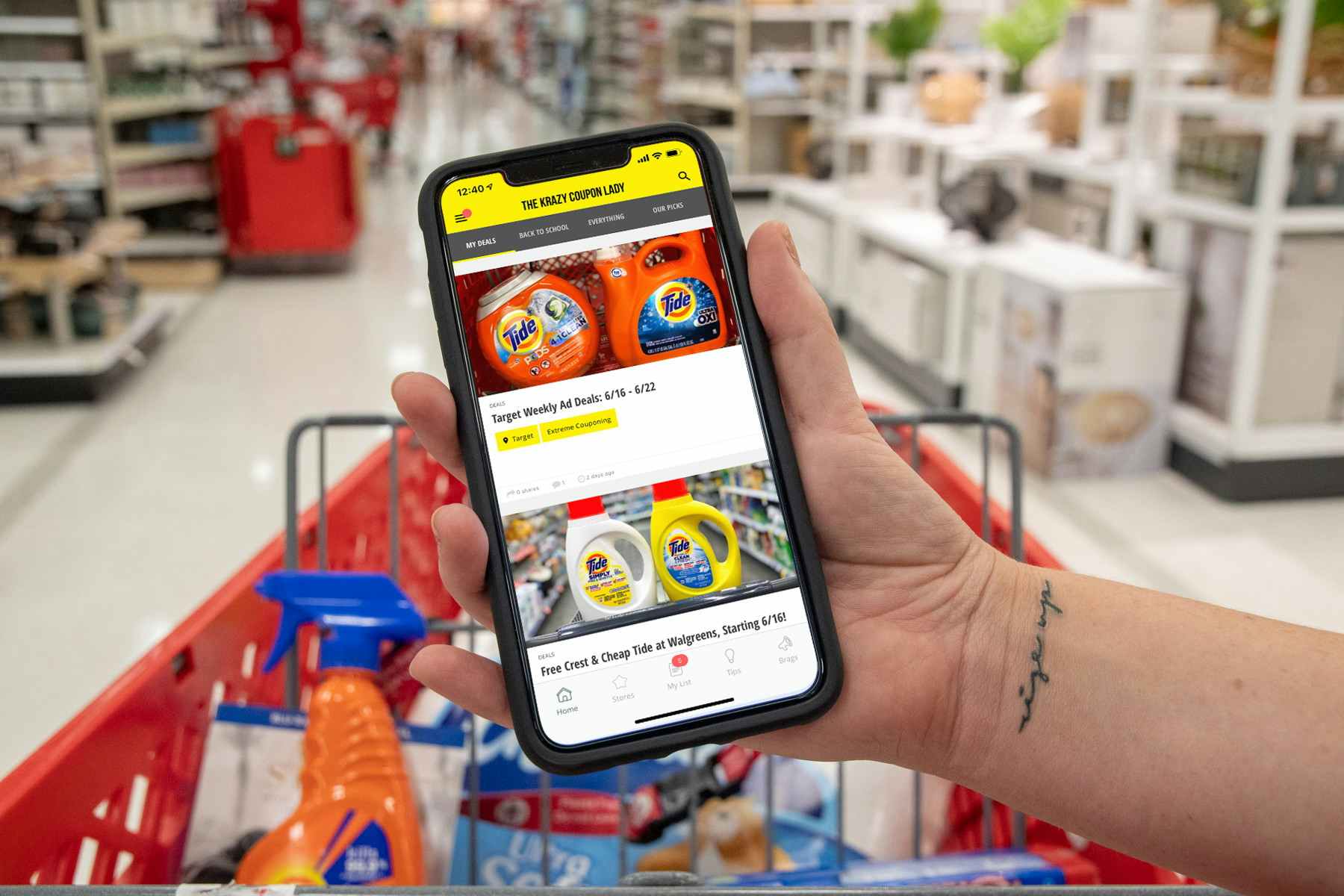 Woman holding and iPhone displaying The Krazy Coupon lady App, inside a Target store with a shopping cart filled with products in the ...