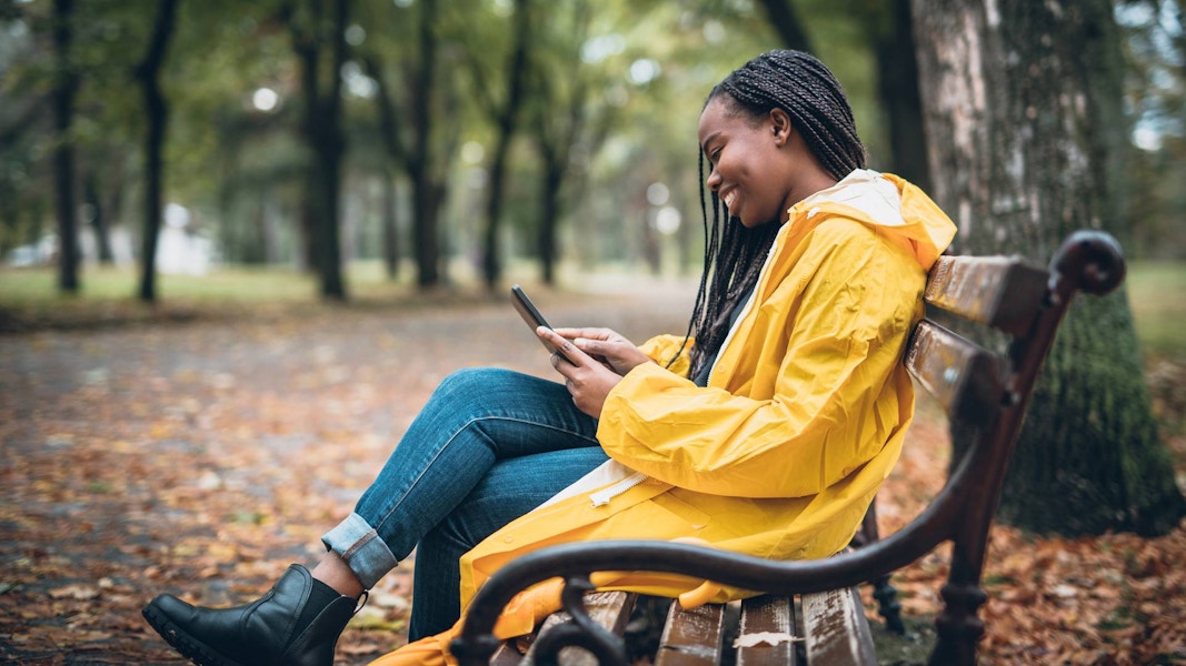 Person Looking at the phone while sitting on a park bench