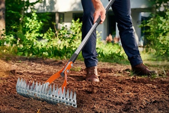 man using rake in yard