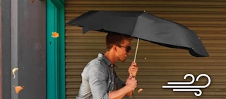 A guy walking with a black umbrella