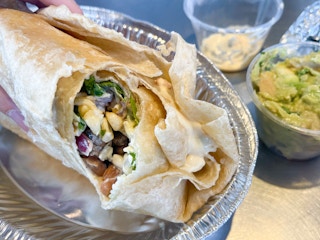 A chipotle secret menu burrito with a second tortilla wrapped around it, queso is visible between the two tortillas.