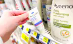 hand grabbing a bottle of Aveeno lotion