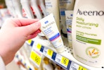 hand grabbing a bottle of Aveeno lotion