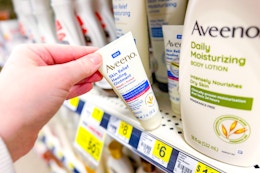 hand grabbing a bottle of Aveeno lotion