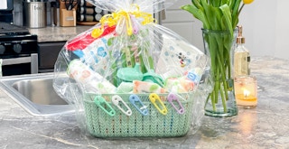 a baby shower gift basket sitting on a kitchen counter next to flowers