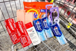 tide pods, monday conditioner, oral b toothbrushes, crest toothpaste, colgate toothpaste, and eucerin lotion in a cart