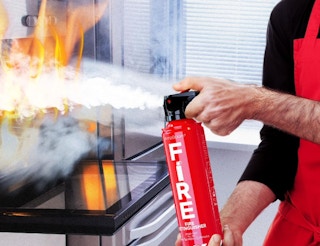 a person putting out a fire with a fire extinguisher