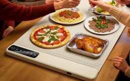 food on plates on a food warming mat at a table 