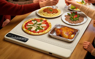 food on plates on a food warming mat at a table