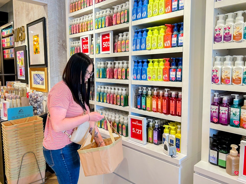 a person putting hand soaps into their basket at bath & body