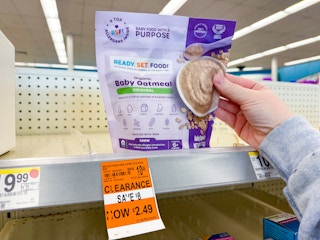 person grabbing a pack of baby oatmeal off the shelf