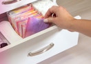 a hand pulling out a wrapped panty liner out of a drawer 