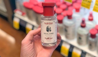 hand holding a travel size bottle of thayers toner in front of a store shelf display
