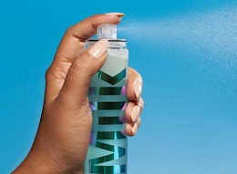 a person spraying a makeup mist 
