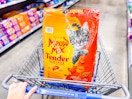 hand pushing walmart cart with a bag of meow mix dry cat food