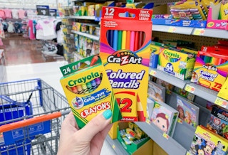 crayola crayons and cra-z-art colored pencils in left hand in front of school supplies and walmart cart