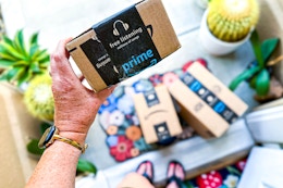 a close up of a hand holding an amazon prime day box in doorway 