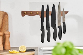 A wood grain magnetic knife holder shaped like a knife hangs on a kitchen wall.
