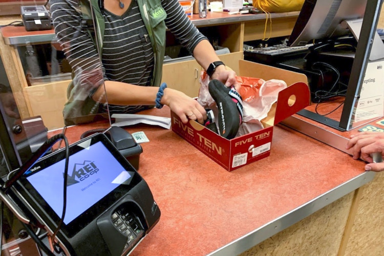 REI employee pulling shoes out of box at the return counter