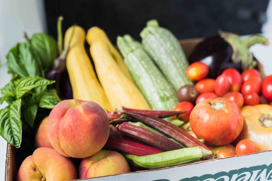 box of fresh produce with peaches, okra, tomato, and squash